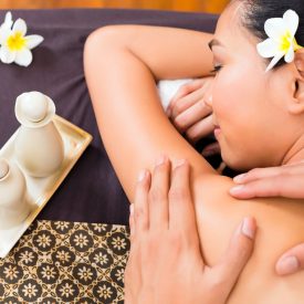 Masseur giving Indonesian Asian woman a aroma therapy massage with essential oil in a beauty wellness spa